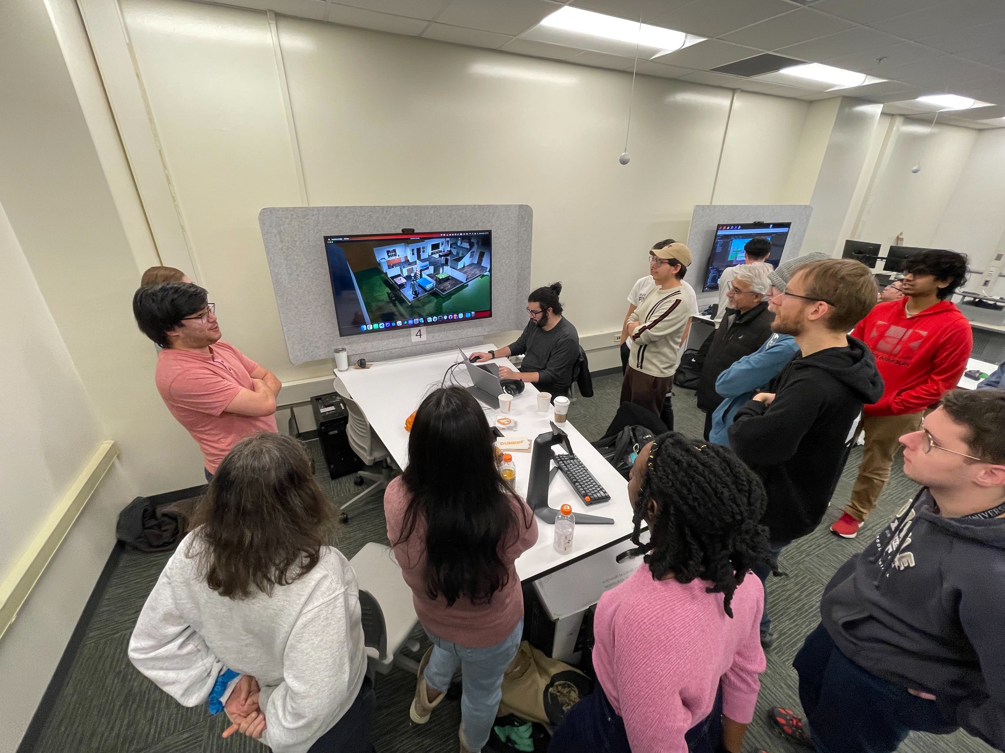 Students gathering around a workstation during a game project demonstration