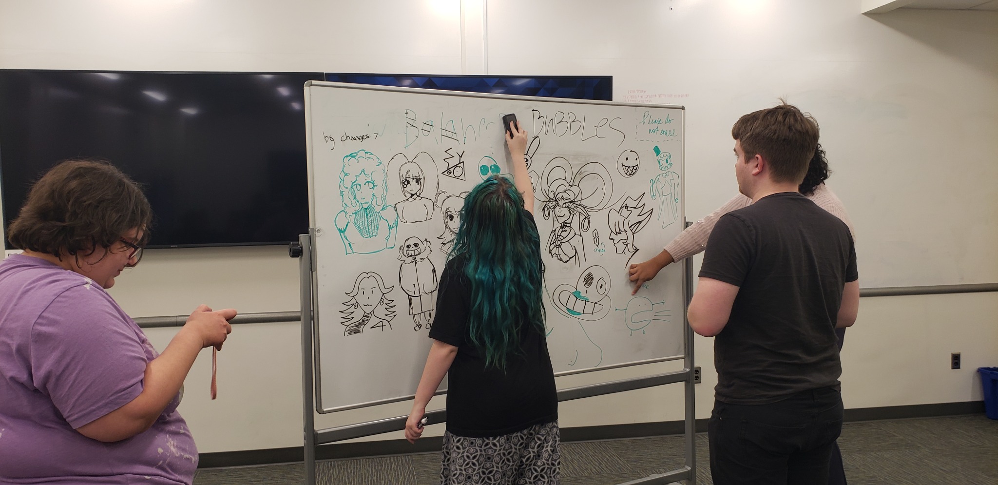 Students drawing characters and ideas on a whiteboard during a game jam