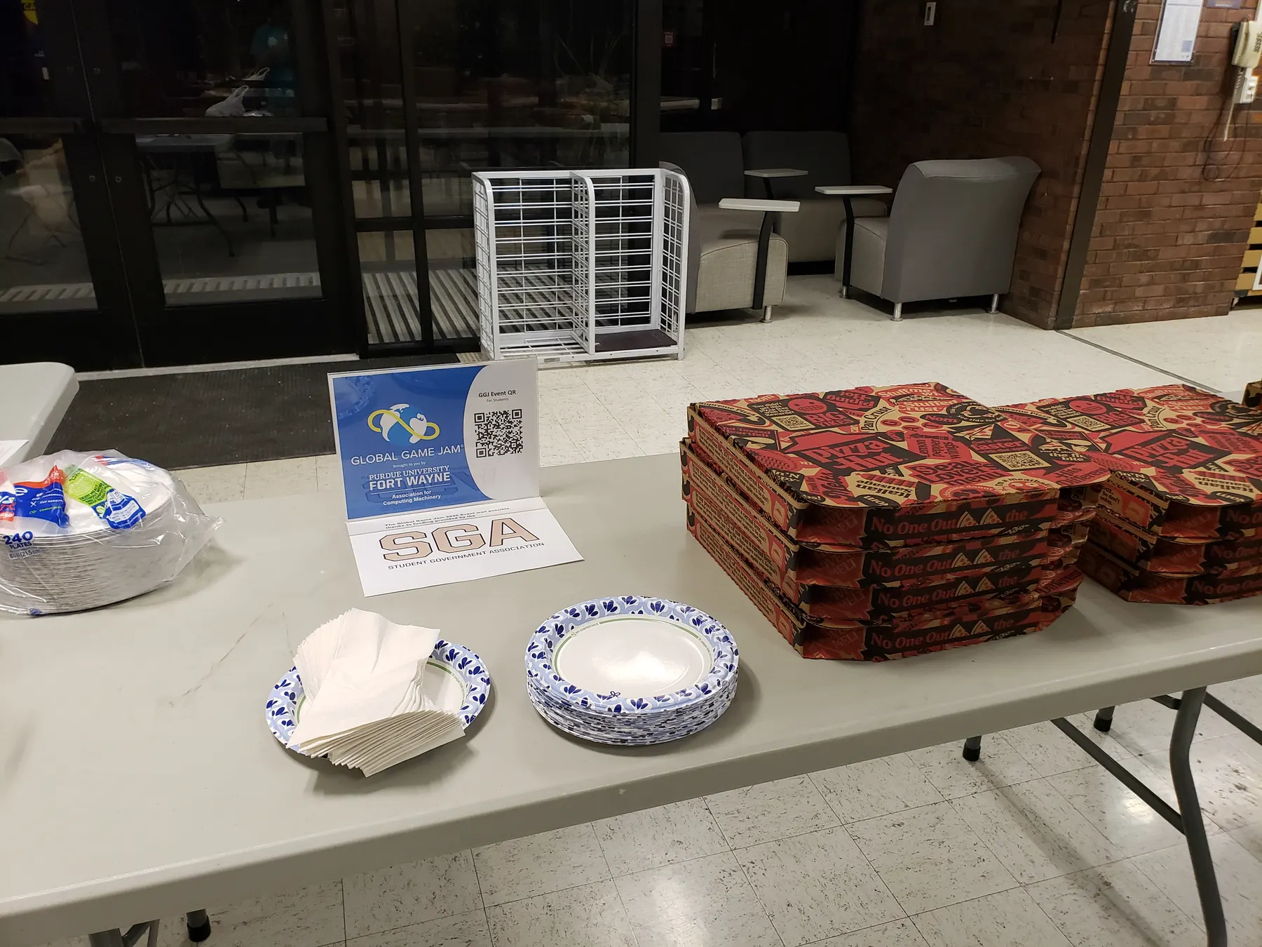 Pizza, snacks, plates, and Global Game Jam signage at the PFW event